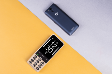 Dva telefony BlindShell Classic 3 v barvách zlatavě pískové a oceánově modré na diagonálně rozděleném žlutém a světle šedém pozadí. Jeden telefon je zobrazen zepředu s velkým kontrastním displejem a hmatovou klávesnicí, druhý zezadu s fotoaparátem, SOS tlačítkem a logem BlindShell.