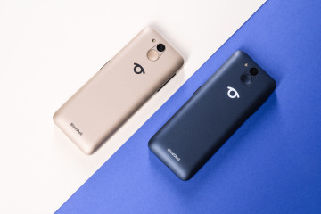 Dva modely telefonu BlindShell Classic 3 zobrazené z pohledu zadní strany, jeden ve zlaté a druhý v tmavě modré barvě. Elegantní design telefonu je zdůrazněn decentním logem BlindShell uprostřed zadní části a čočkou fotoaparátu s kruhovým prvkem v horní části. Povrchy obou telefonů jsou matné.
