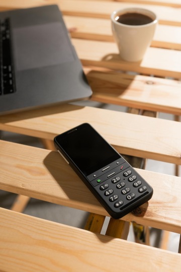 Černý telefon BlindShell Classic 2, ležící na stole