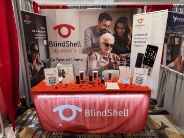 Stánek BlindShell Classic 3, který zaujme výraznou červenou barvou, bannery s informacemi o produktech a přitažlivým prezentačním prostorem s přístupnými mobilními telefony. Tohle uspořádání odráží naše inovace, zaměření na nezávislost a podporu asistenčních technologií.
